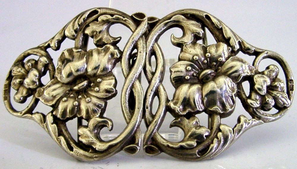 A two-piece cast sterling silver Art Nouveau belt buckle featuring relief floral and foliage motifs.