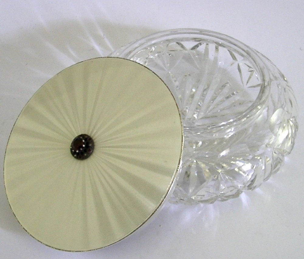 A circular cut glass dressing table jar topped with a white guilloche enamel and sterling silver lid. View IV
