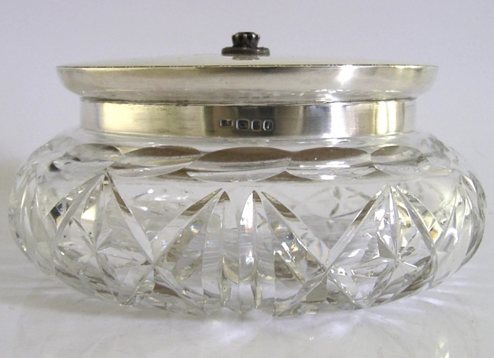 A circular cut glass dressing table jar topped with a white guilloche enamel and sterling silver lid. View VI