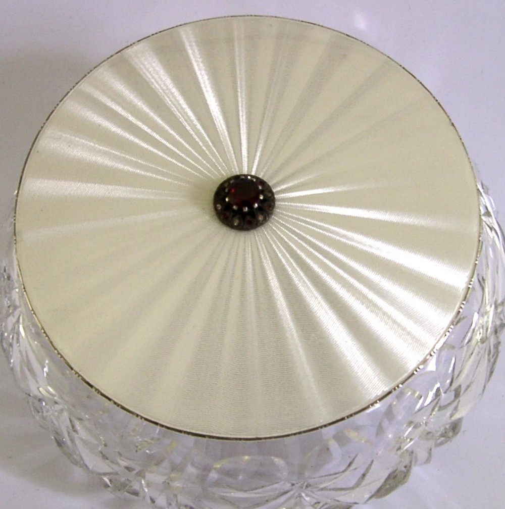 A circular cut glass dressing table jar topped with a white guilloche enamel and sterling silver lid. View VII