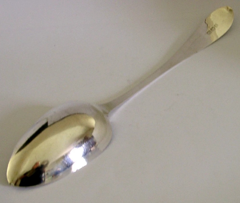 A Georgian sterling silver basting spoon with a Celtic point handle featuring bright-cut engraving and a slatted strainer divider inside the bowl. View VII