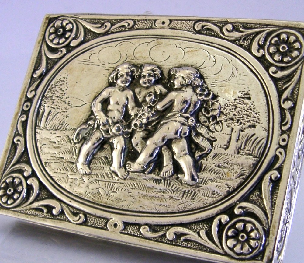 A rectangular silver trinket box featuring an embossed relief scene of three cherubs inside an oval medallion on the hinged lid. View IV
