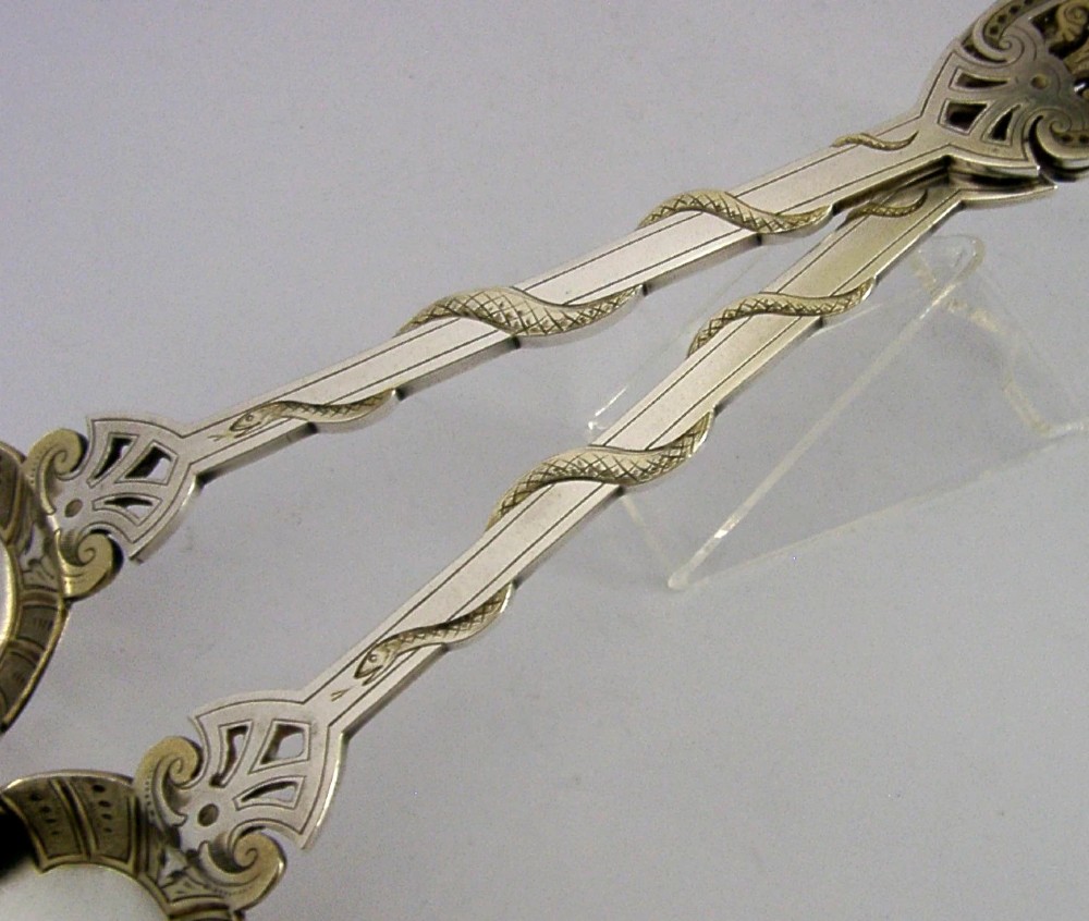 A pair of Victorian silver-plated serving spoons featuring handles entwined with relief-moulded snakes and engraved oval bowls with gilded borders. View II