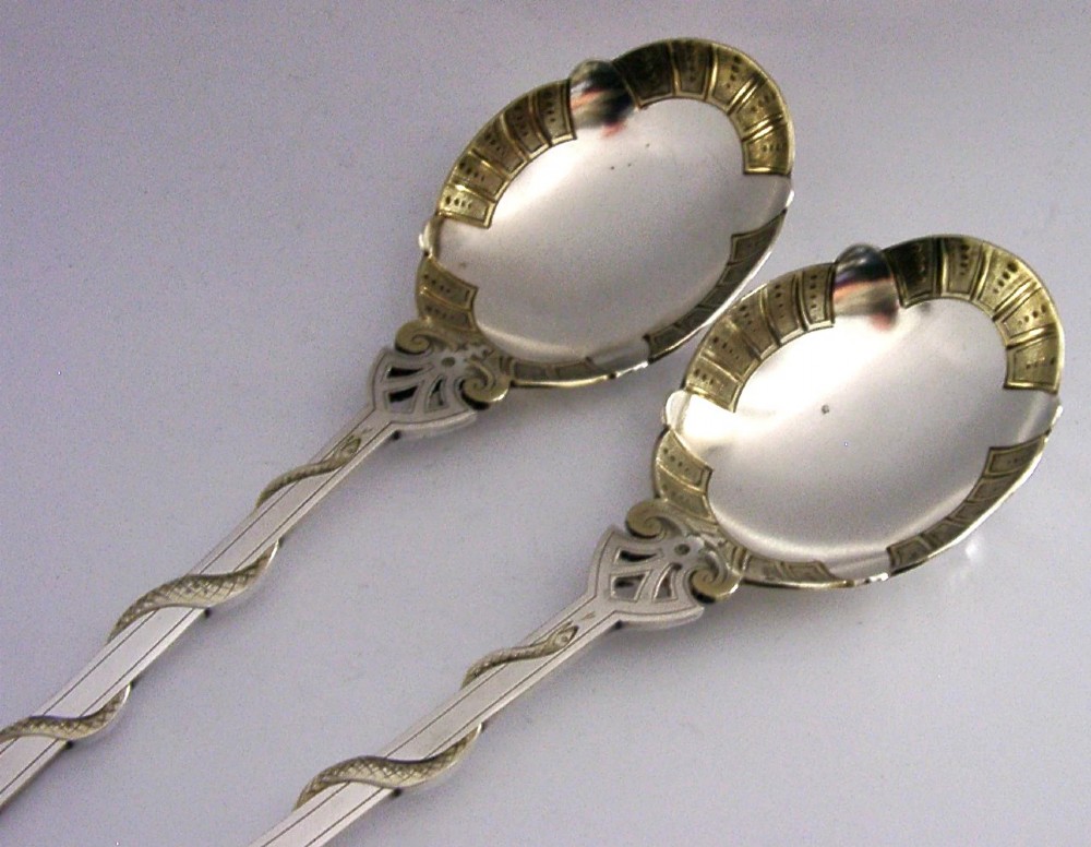 A pair of Victorian silver-plated serving spoons featuring handles entwined with relief-moulded snakes and engraved oval bowls with gilded borders. View IV
