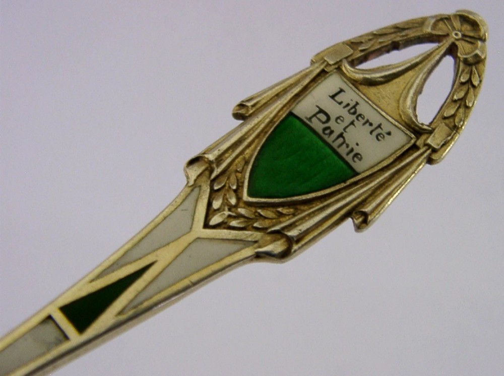 An antique solid silver souvenir spoon featuring a hand-painted enamelled bowl depicting a portrait of a Swiss woman in traditional attire, complete with a green enamelled handle terminal. View VIII