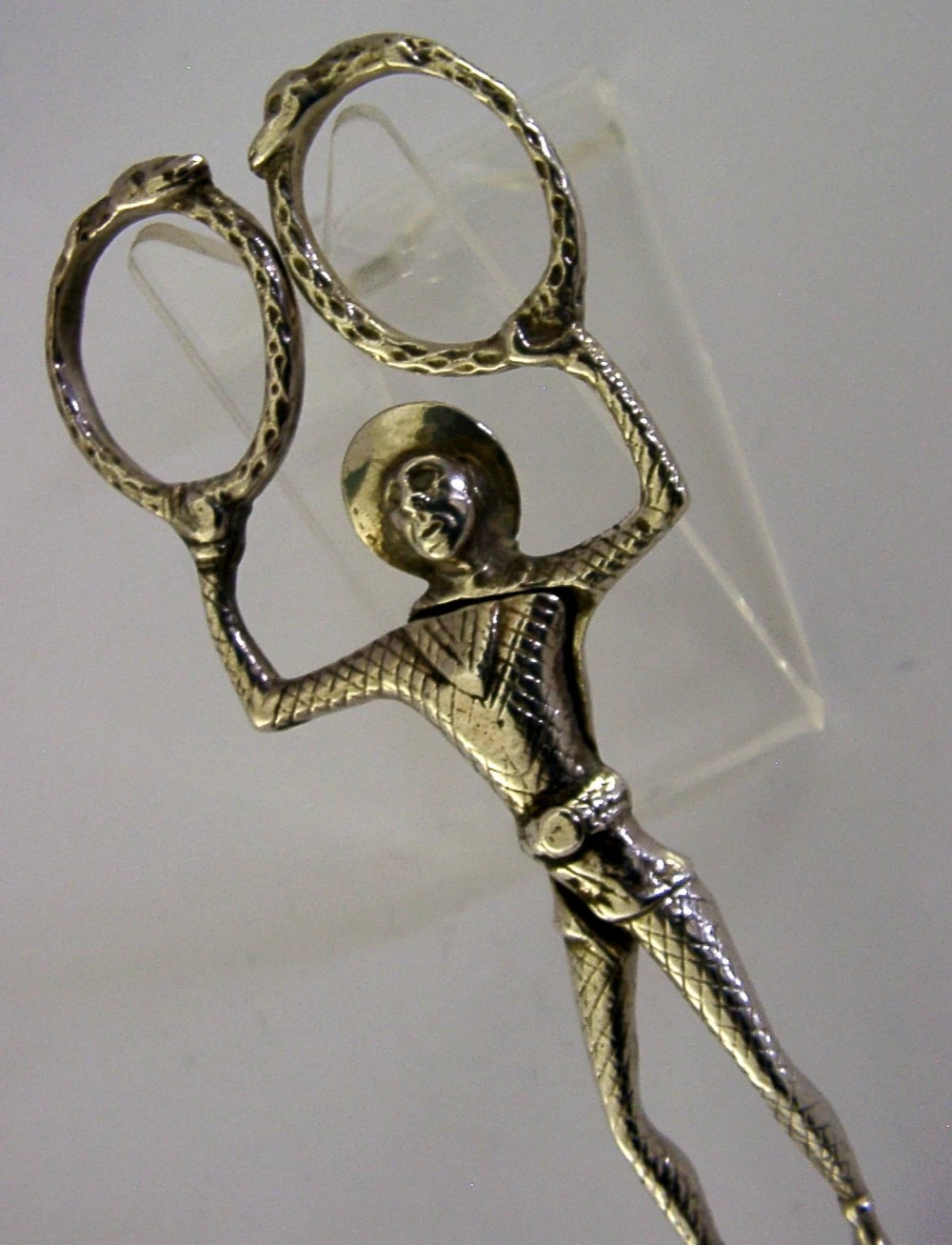 An Edwardian sterling silver sugar nip designed in the detailed shape of a harlequin jester with scissor-action handles and shell-shaped grips. View IV