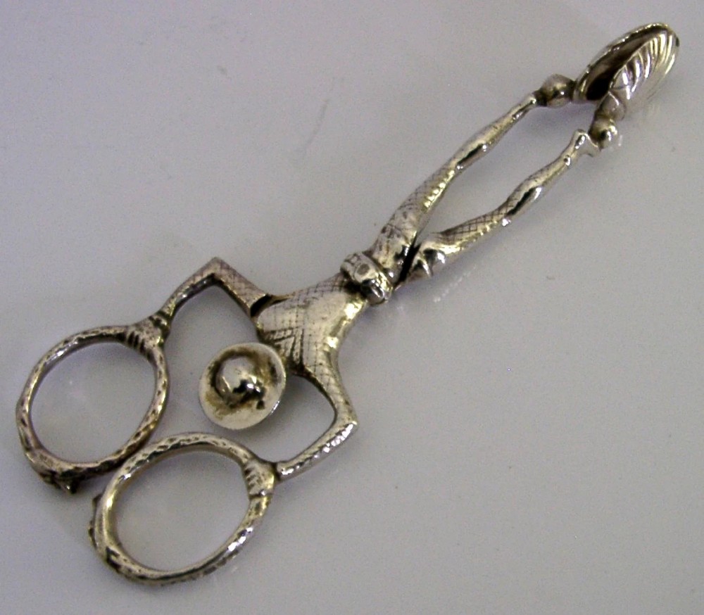 An Edwardian sterling silver sugar nip designed in the detailed shape of a harlequin jester with scissor-action handles and shell-shaped grips. View V