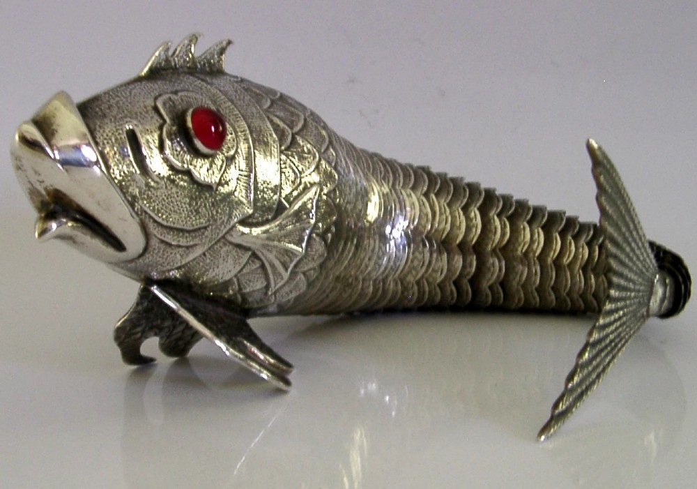 A mid-twentieth-century Spanish 915 silver articulated fish figure with engraved scales, structured fins, and a red cabochon eye.