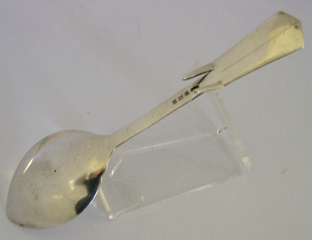 An English sterling silver honey spoon featuring a polished oval bowl, a hooked handle, and detailed Celtic knotwork decoration. View IV