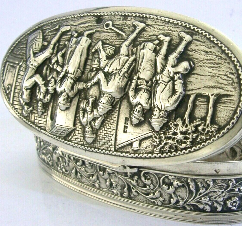 An oval solid silver desk box decorated with high-relief repousse relief depicting traditional Dutch tavern dancers and musicians. View III