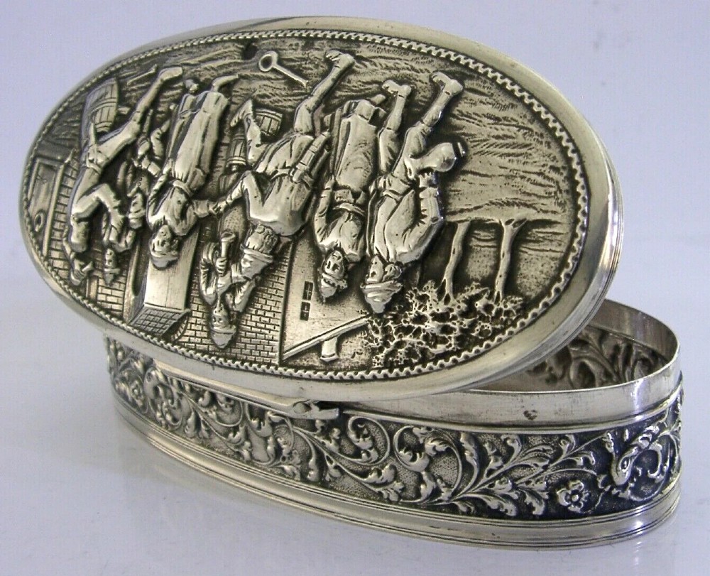 An oval solid silver desk box decorated with high-relief repousse relief depicting traditional Dutch tavern dancers and musicians. View IV