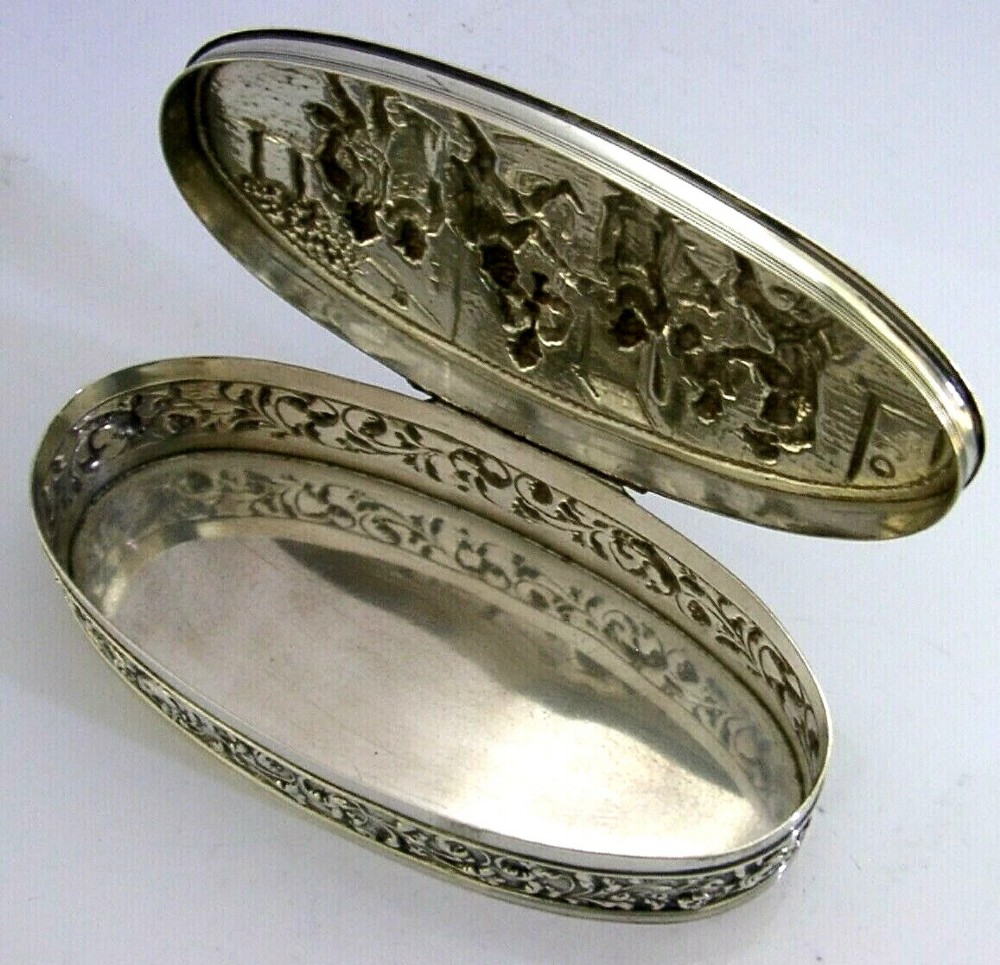 An oval solid silver desk box decorated with high-relief repousse relief depicting traditional Dutch tavern dancers and musicians. View VI