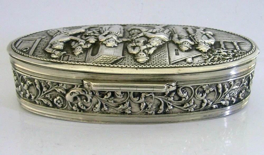 An oval solid silver desk box decorated with high-relief repousse relief depicting traditional Dutch tavern dancers and musicians. View VII
