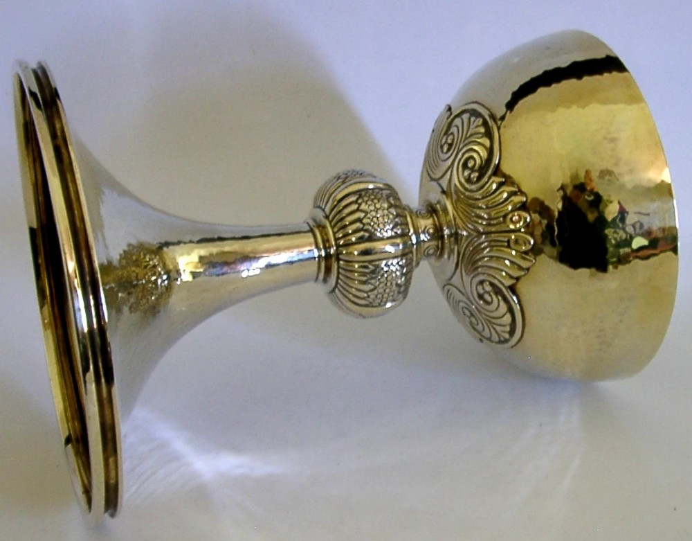 A gold-coloured sterling silver-gilt chalice with a hand-hammered bowl, a decorative knop stem, and a Celtic cross emblem on the flared base. View VIII