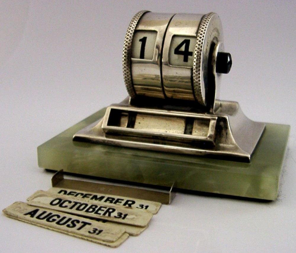 An Art Deco sterling silver mechanical perpetual desk calendar featuring double number rollers mounted on a rectangular pale green onyx base.