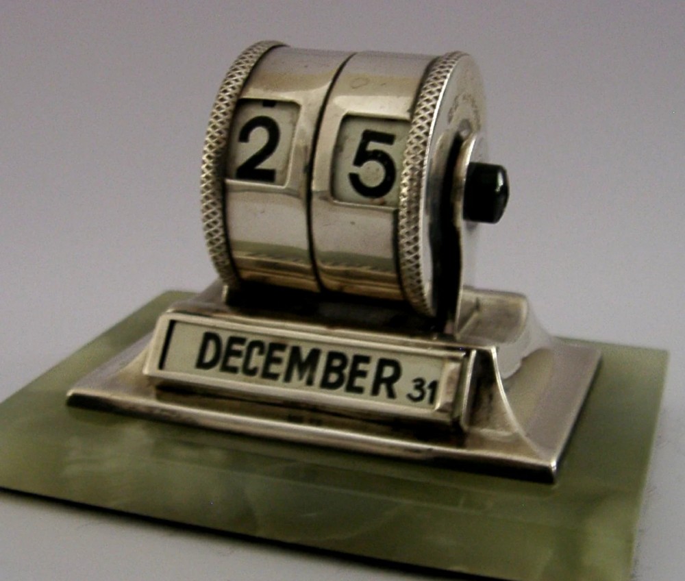 An Art Deco sterling silver mechanical perpetual desk calendar featuring double number rollers mounted on a rectangular pale green onyx base. View VI