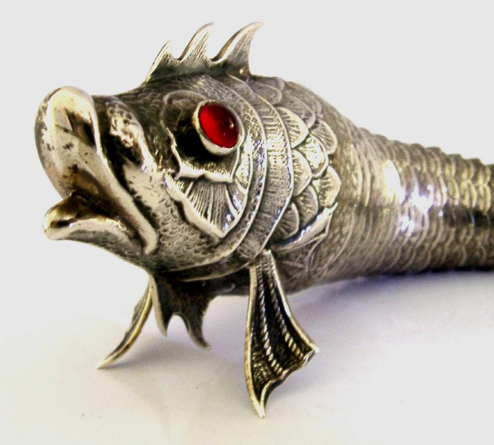A Spanish silver articulated fish featuring overlapping jointed scales, carved fins, and red cabochon eyes. View II