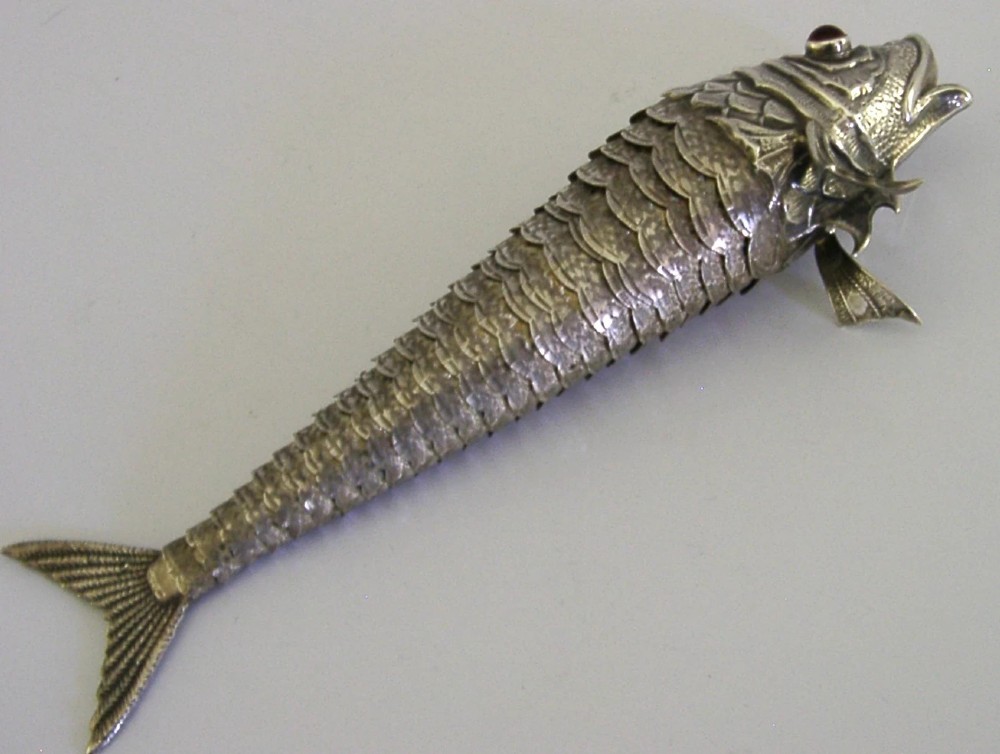 A Spanish silver articulated fish featuring overlapping jointed scales, carved fins, and red cabochon eyes. View III