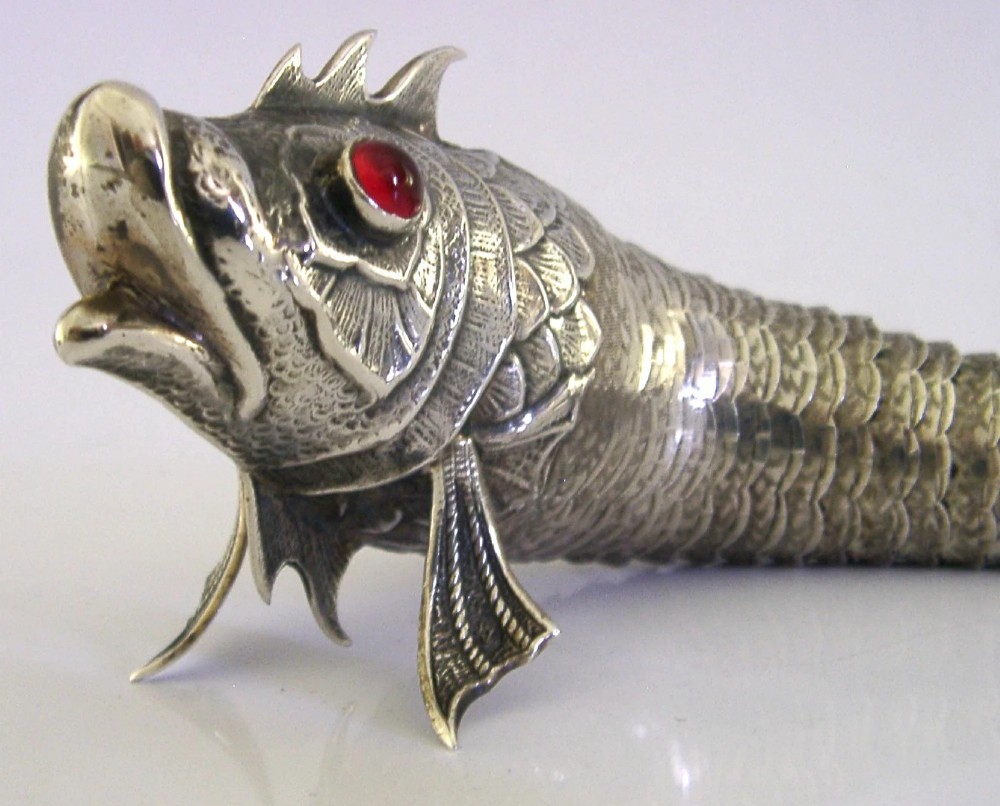 A Spanish silver articulated fish featuring overlapping jointed scales, carved fins, and red cabochon eyes. View IV