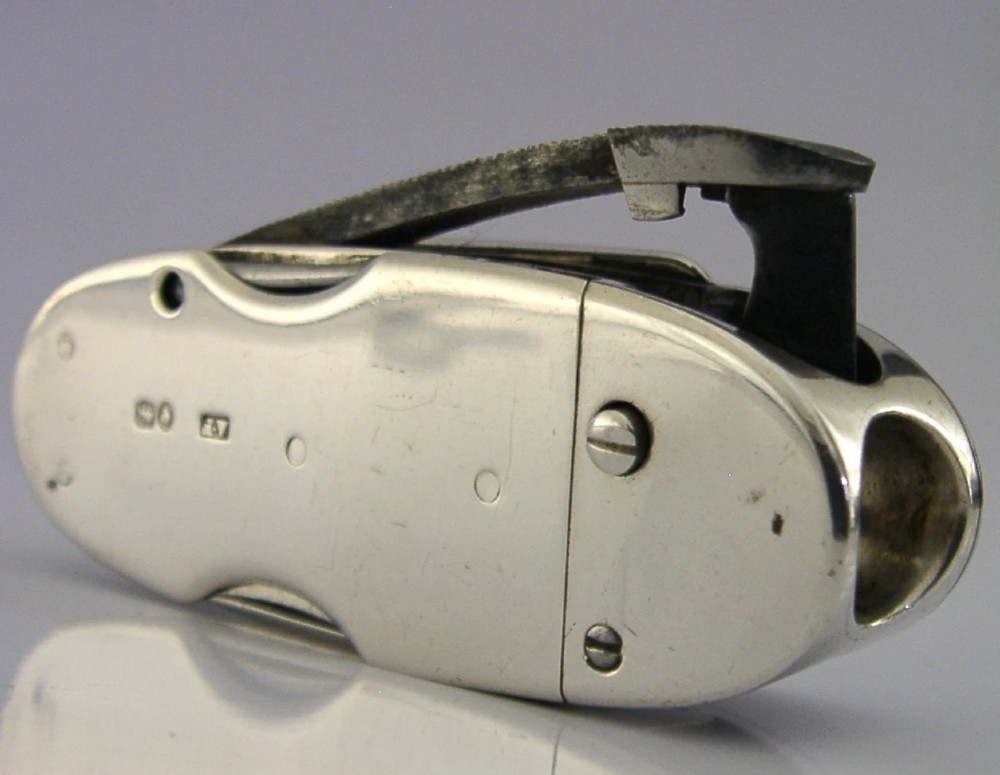A Victorian sterling silver cigar cutter multi-tool with hallmarked silver casing and open fold-out steel implement.