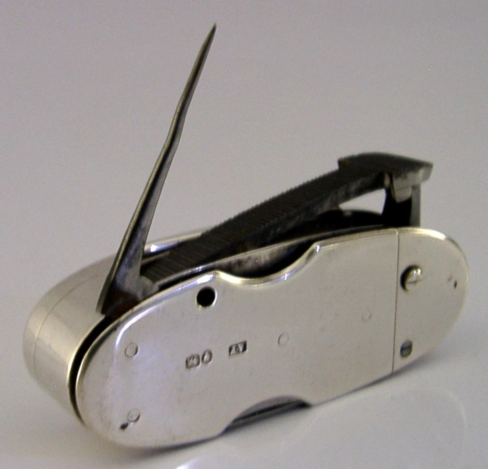 A Victorian sterling silver cigar cutter multi-tool with hallmarked silver casing and open fold-out steel implement. View IV