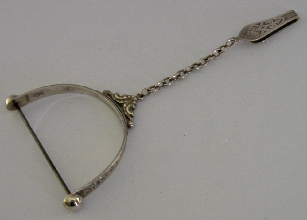 A Victorian sterling silver chatelaine thread spool holder featuring engraved scrollwork motifs and suspension chains. View II