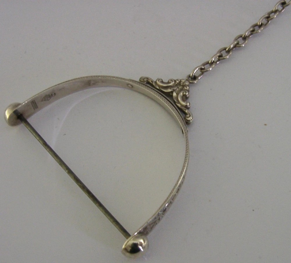 A Victorian sterling silver chatelaine thread spool holder featuring engraved scrollwork motifs and suspension chains. View IV