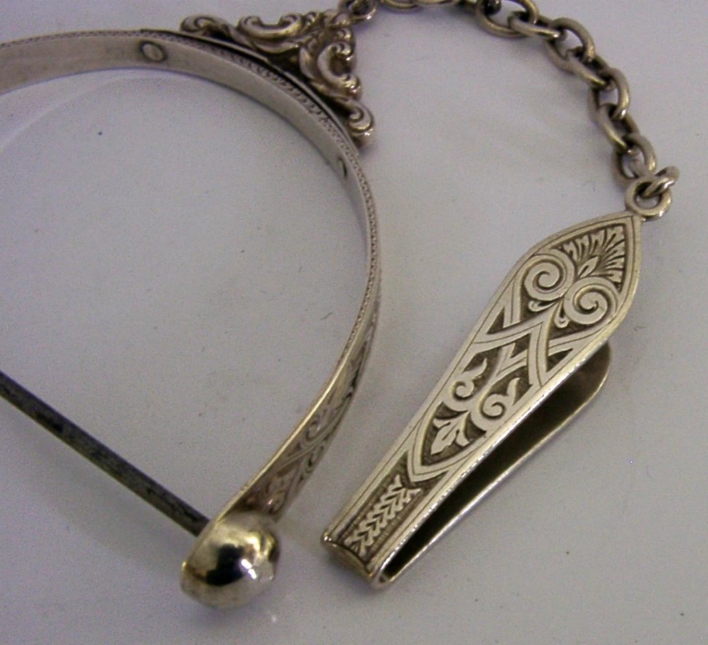 A Victorian sterling silver chatelaine thread spool holder featuring engraved scrollwork motifs and suspension chains. View V