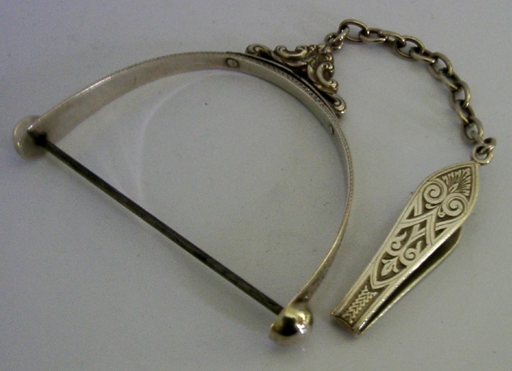A Victorian sterling silver chatelaine thread spool holder featuring engraved scrollwork motifs and suspension chains. View IX