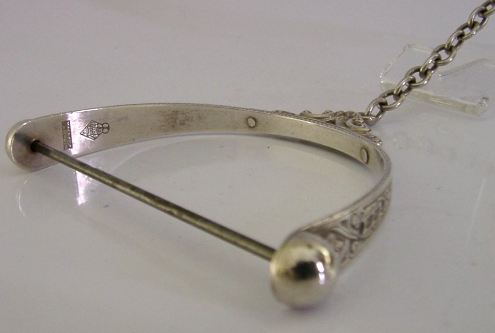 A Victorian sterling silver chatelaine thread spool holder featuring engraved scrollwork motifs and suspension chains. View X