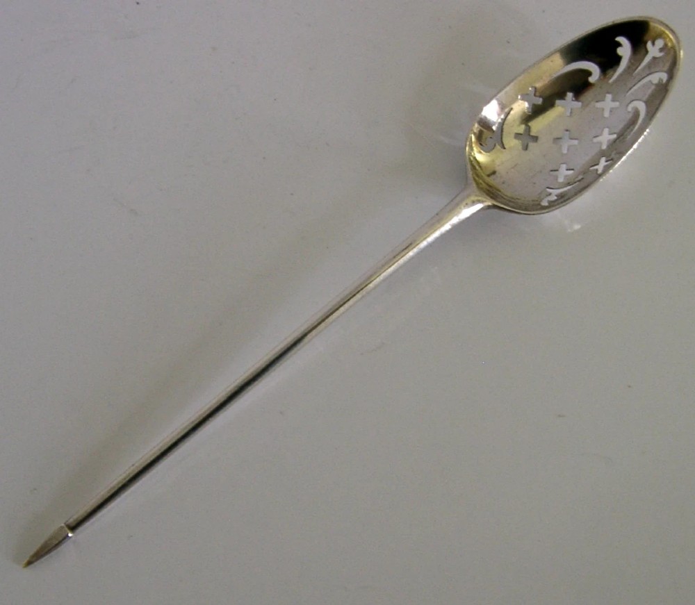 An 18th-century Georgian sterling silver mote spoon with a hand-pierced bowl featuring scroll cutouts and a long stem ending in a pointed tip.