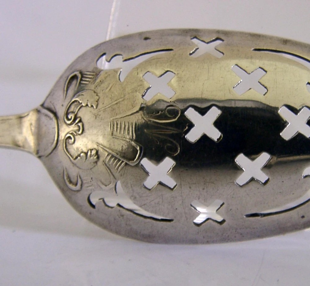 An 18th-century Georgian sterling silver mote spoon with a hand-pierced bowl featuring scroll cutouts and a long stem ending in a pointed tip. View II