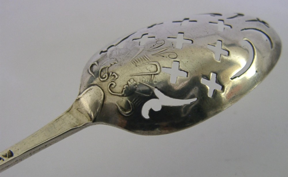 An 18th-century Georgian sterling silver mote spoon with a hand-pierced bowl featuring scroll cutouts and a long stem ending in a pointed tip. View V