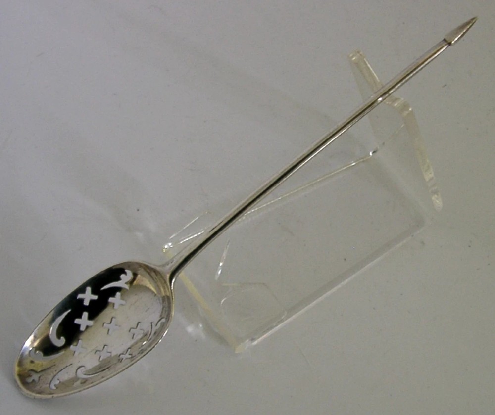An 18th-century Georgian sterling silver mote spoon with a hand-pierced bowl featuring scroll cutouts and a long stem ending in a pointed tip. View VI