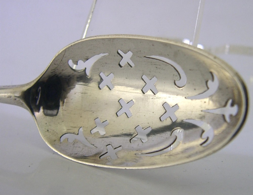 An 18th-century Georgian sterling silver mote spoon with a hand-pierced bowl featuring scroll cutouts and a long stem ending in a pointed tip. View X