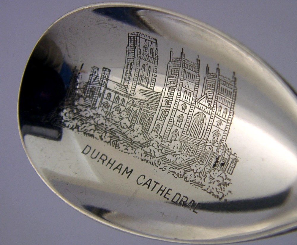 An Edwardian sterling silver tea caddy spoon featuring an engraved illustration of Durham Cathedral in the bowl and the Sanctuary Knocker on the handle. View V