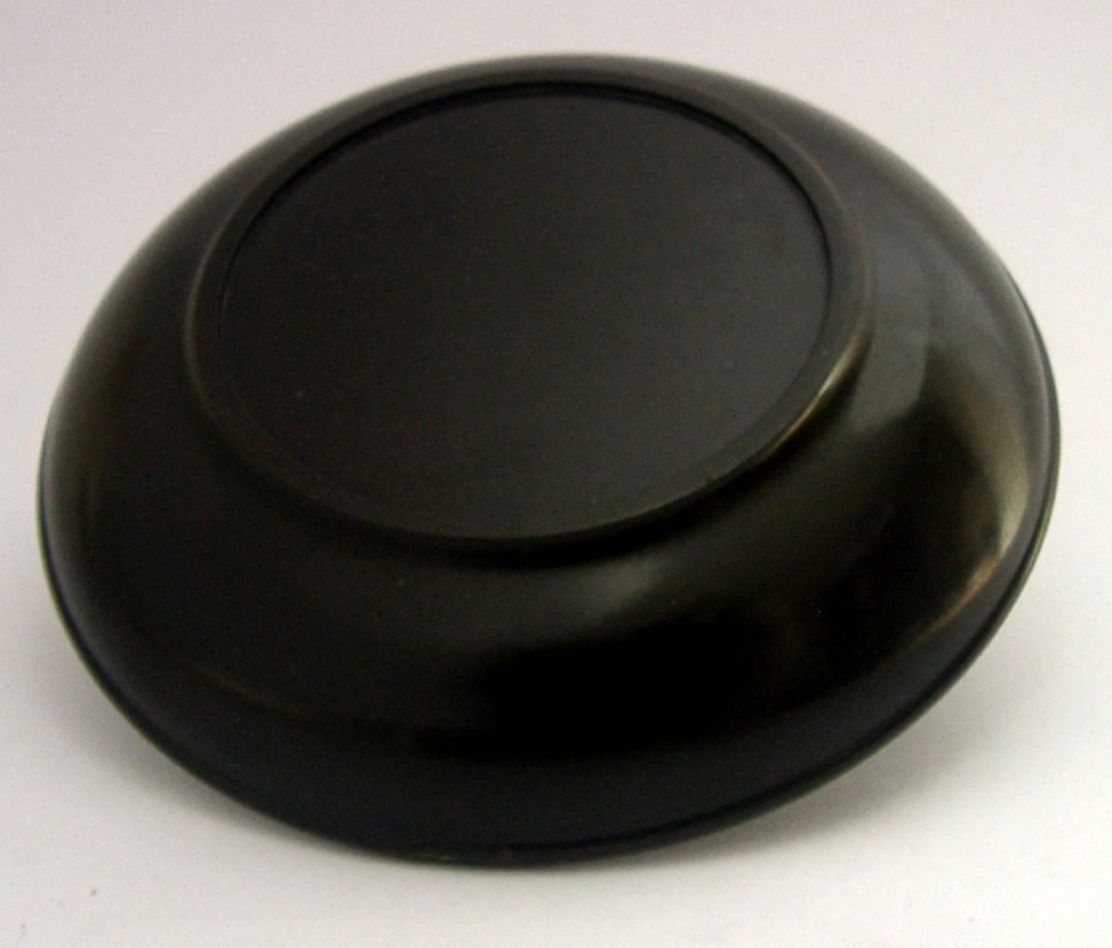 A circular black Bakelite dish featuring a central sterling silver overlay depicting the sailing ship HMS Victory. View V