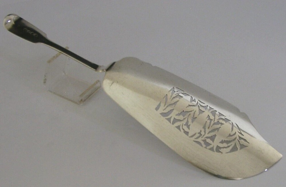 A Victorian sterling silver fish server featuring an intricately engraved blade with foliate patterns and a flat handle. View VI