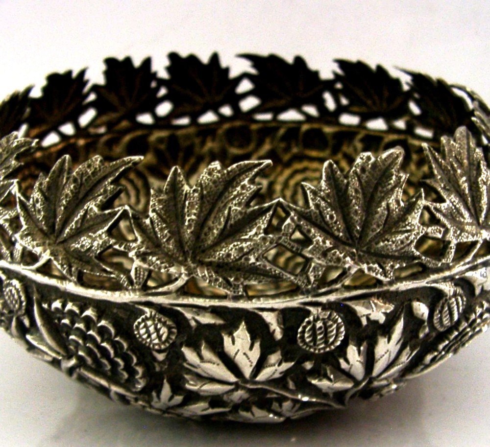A rounded solid silver bowl featuring detailed repousse floral and foliate hand-chased decoration with a circular central polished medallion. View II