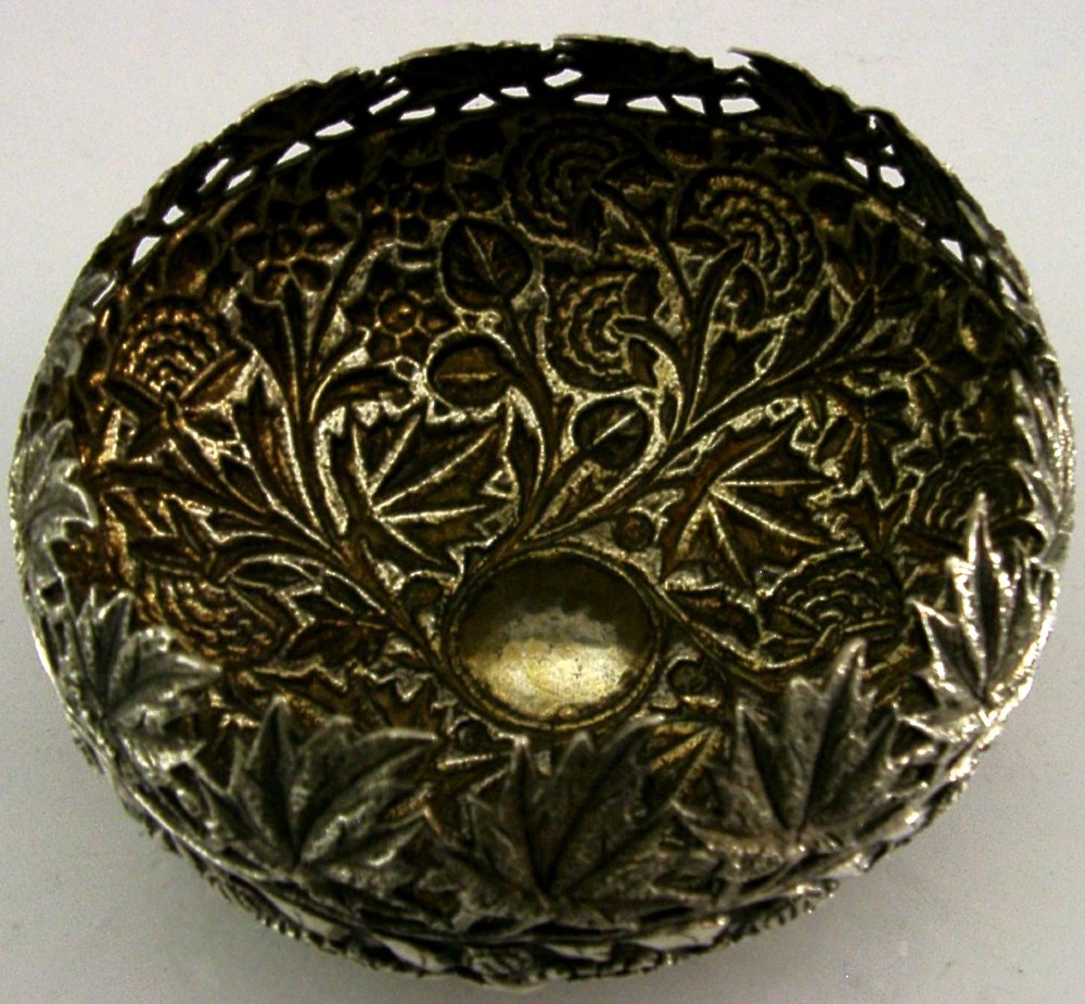 A rounded solid silver bowl featuring detailed repousse floral and foliate hand-chased decoration with a circular central polished medallion. View V
