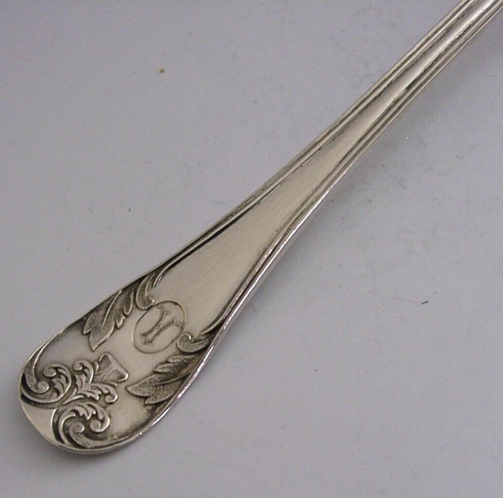 An antique solid silver sugar sifter spoon featuring a round perforated bowl and an engraved foliate handle dated 1903. View III