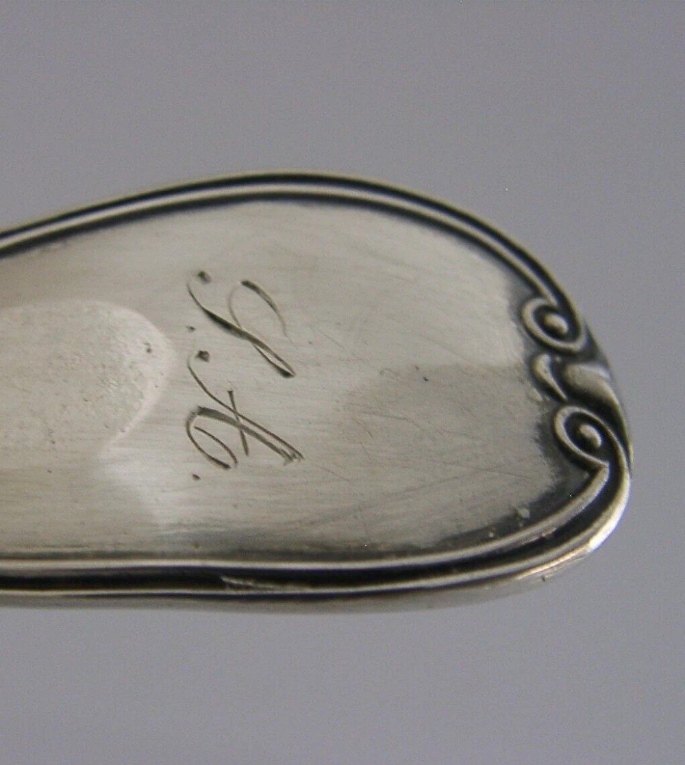 An antique solid silver sugar sifter spoon featuring a round perforated bowl and an engraved foliate handle dated 1903. View V