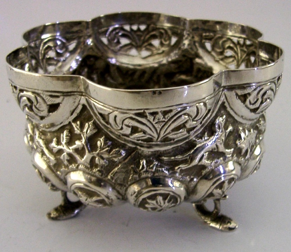 A small footed solid silver bowl featuring intricate repousse floral and animal motifs with a scalloped rim. View II