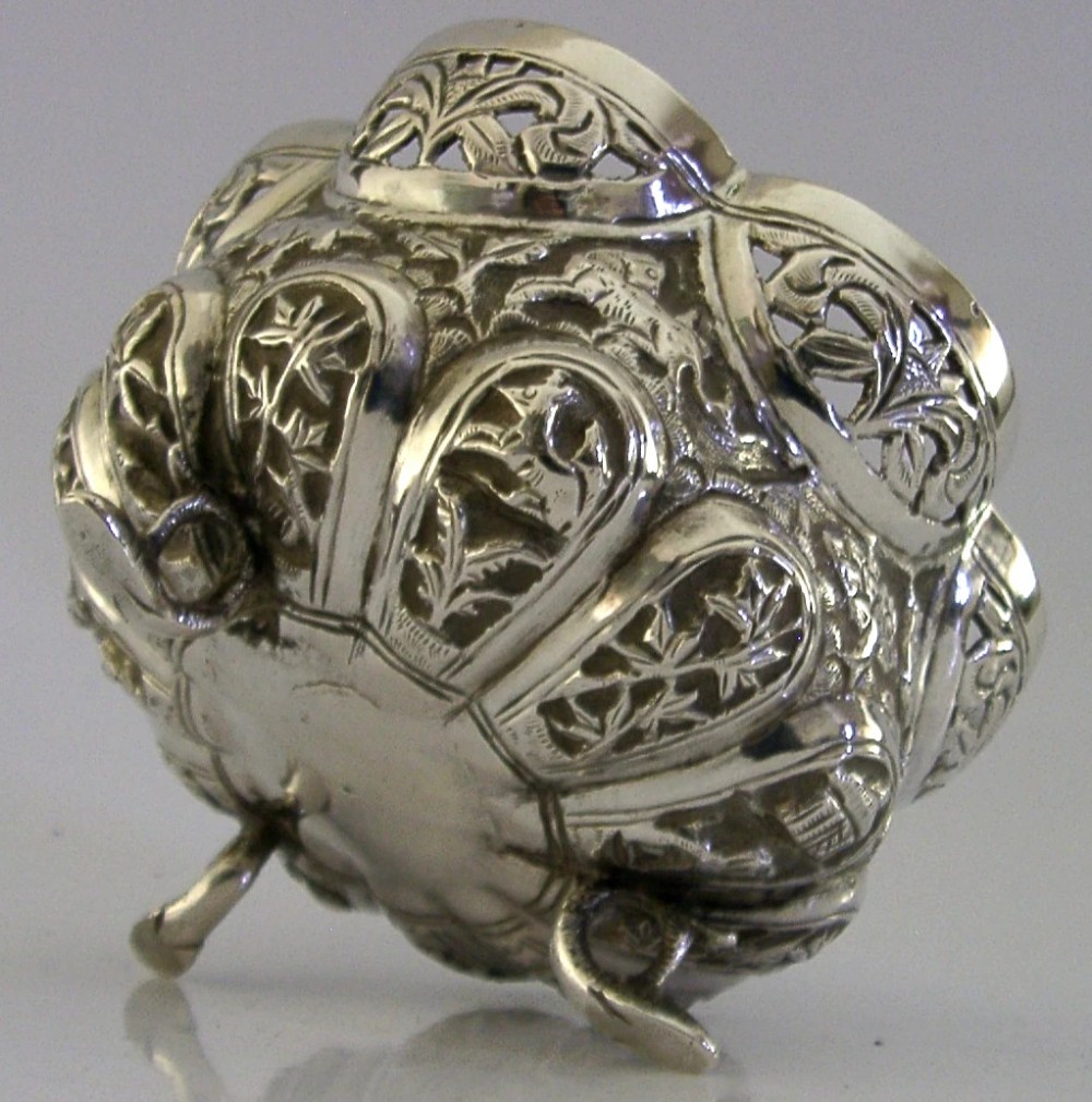A small footed solid silver bowl featuring intricate repousse floral and animal motifs with a scalloped rim. View V