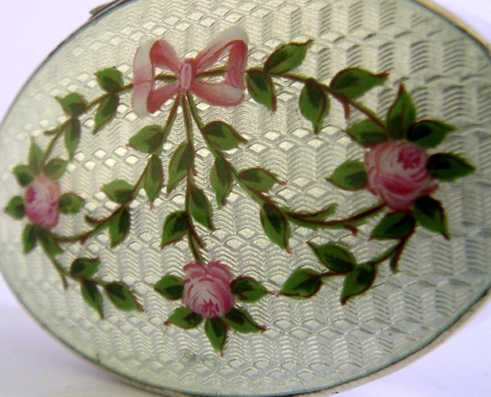An oval sterling silver trinket box featuring a light blue guilloche enamel lid detailed with hand-painted pink roses and a ribbon garland. View II
