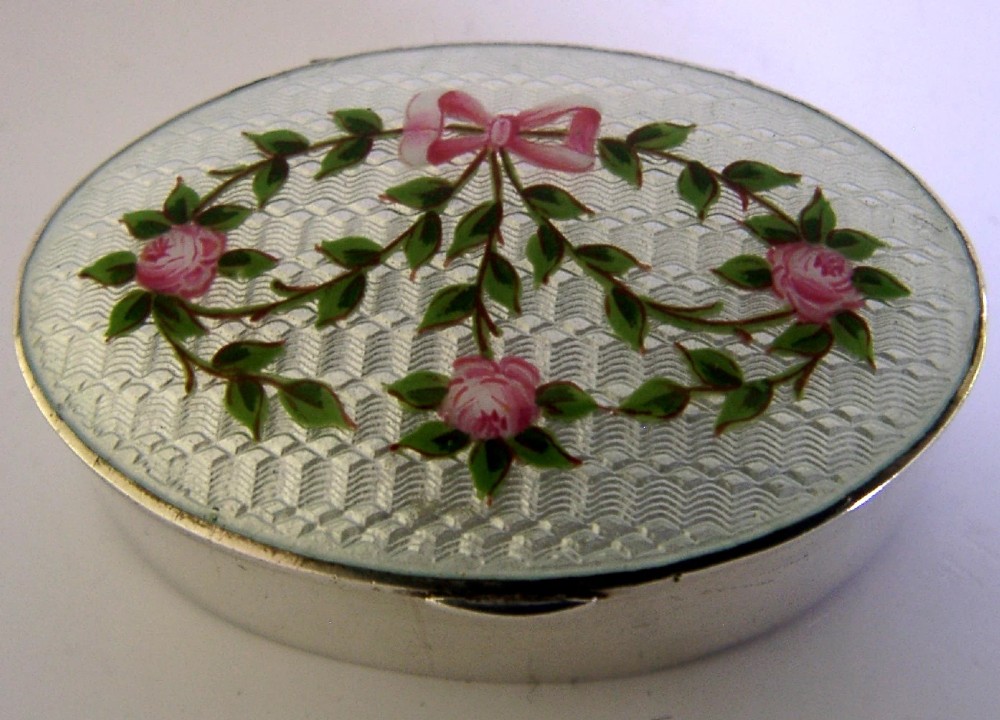 An oval sterling silver trinket box featuring a light blue guilloche enamel lid detailed with hand-painted pink roses and a ribbon garland. View IV