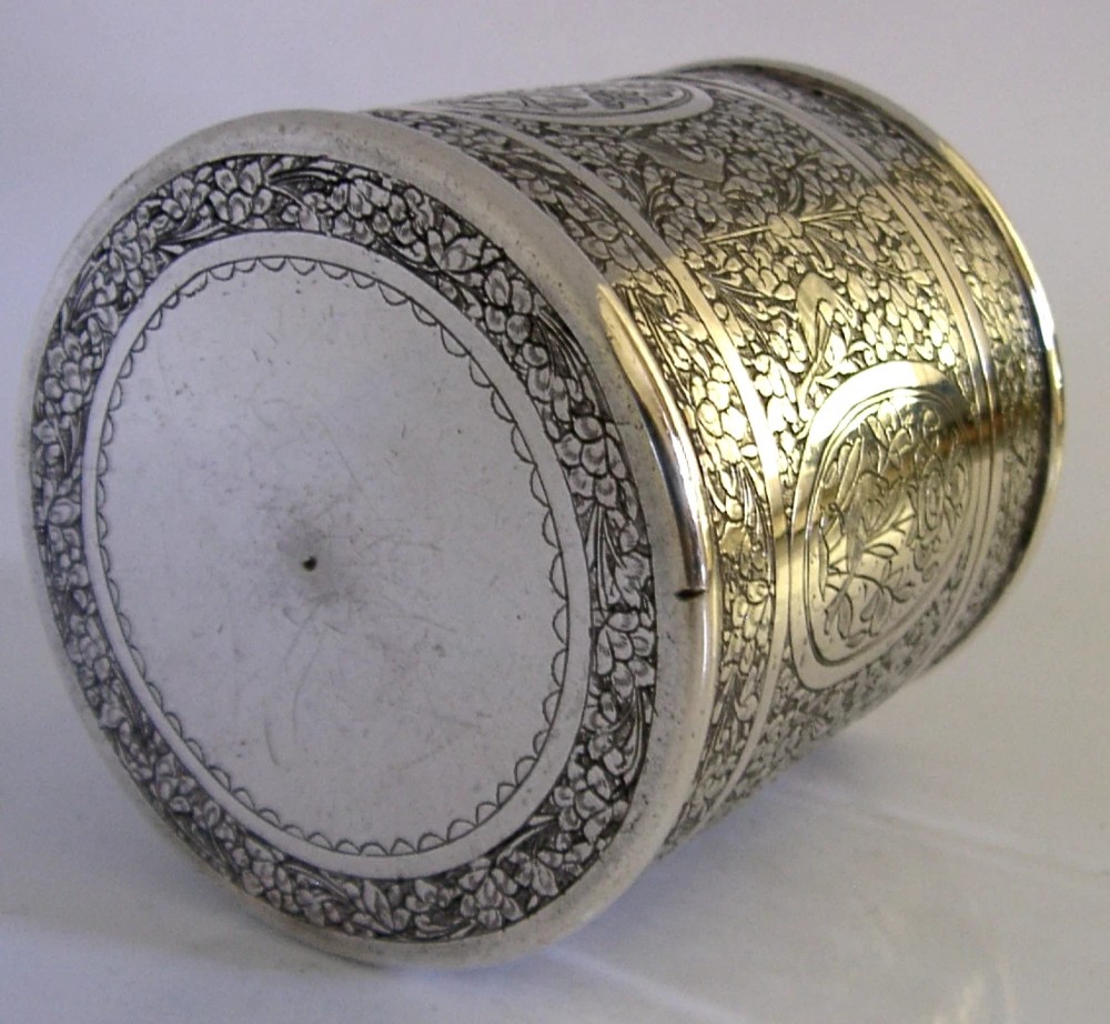 A cylindrical solid silver tea caddy featuring intricate chased floral and bird designs with a pierced pattern top lid. View VIII