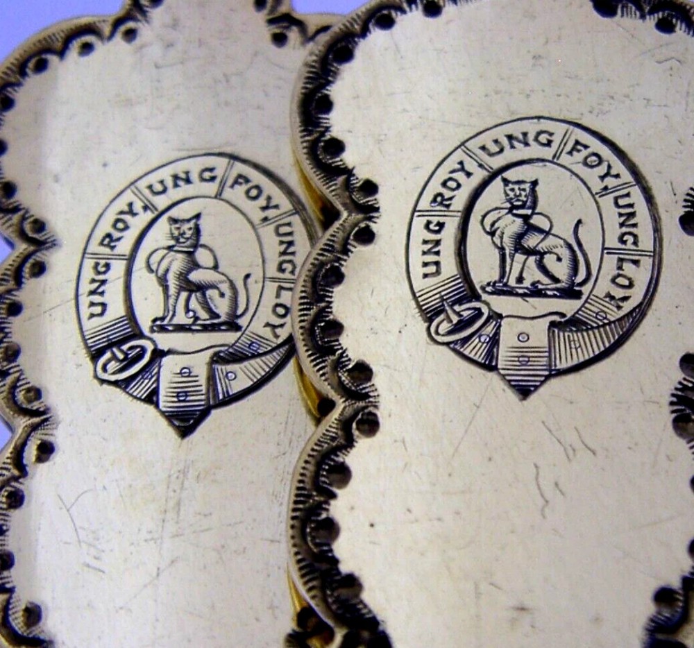 A pair of Edwardian sterling silver gilt serving spoons featuring deep oval bowls and engraved family crests on the terminals. View II