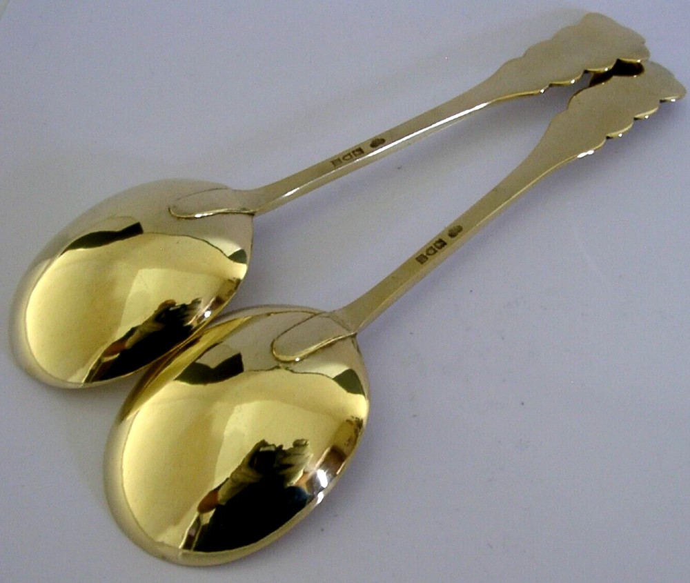 A pair of Edwardian sterling silver gilt serving spoons featuring deep oval bowls and engraved family crests on the terminals. View III