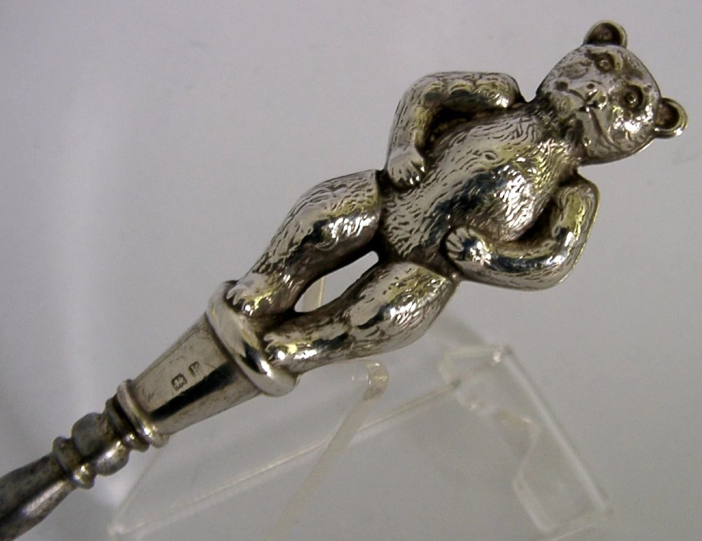 An Edwardian sterling silver button hook featuring a figurative teddy bear handle connected to a long steel shaft. View IV